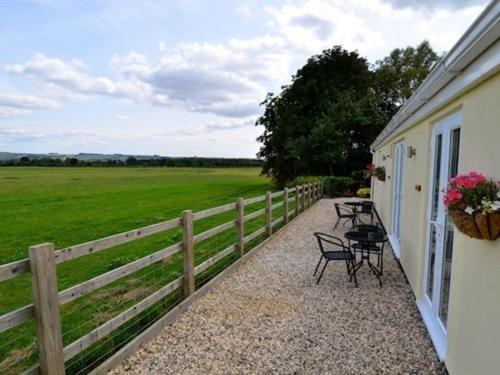 a porch with chairs and a fence and a field at The White Horse View B&B in Shrivenham