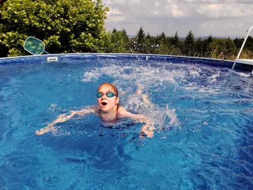 a woman in a swimming pool wearing sunglasses at Zagroda na Pacanach in Iwkowa