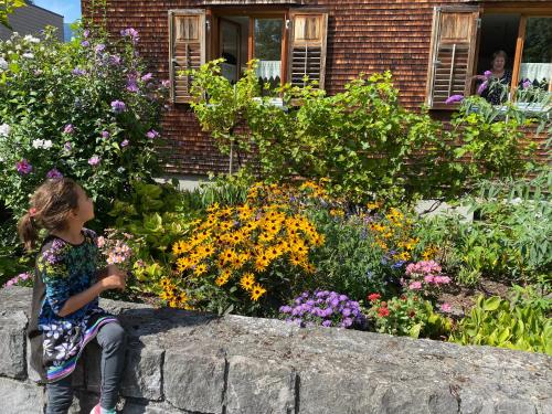 a little girl sitting on a stone wall in a garden at mama käthe - Apartments in Nenzing