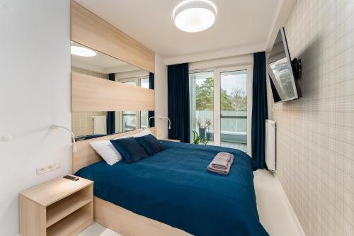 a bedroom with a blue bed and a window at Sunrise Apartament in Rogowo