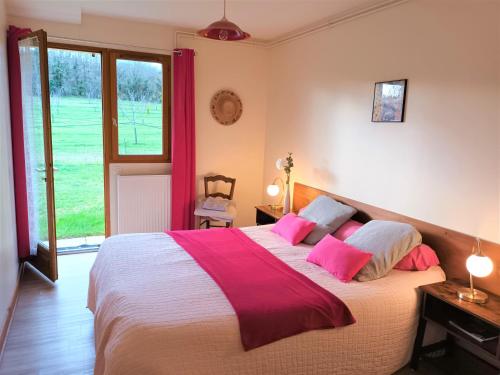 a bedroom with a large bed with pink pillows at au bonheur du cedre in Saint-Lattier