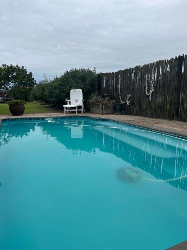 a swimming pool with a white chair next to a fence at De Oude Mayde in Wilderness