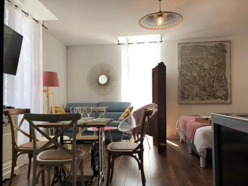 un salon avec une table, des chaises et un canapé dans l'établissement LES APPART'S DES DEMOISELLES DE ROCHEFORT, à Rochefort