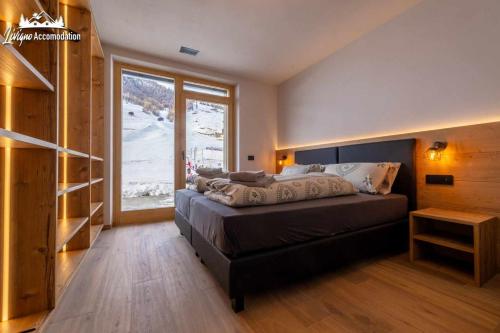 a bedroom with a bed and a large window at Radici Relais Sulle Piste da sci vicino a Lupigno in Livigno