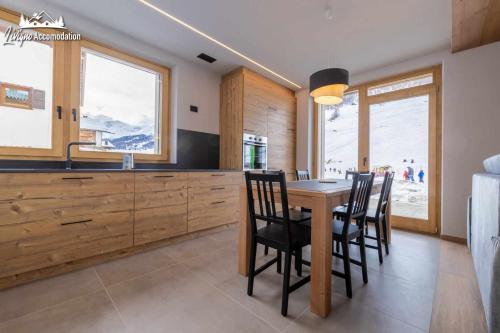 a kitchen with a wooden table and chairs and a sink at Radici Relais Sulle Piste da sci vicino a Lupigno in Livigno