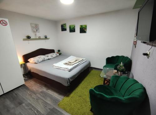 a bedroom with a bed and two green chairs at VINI studio with private parking in Skopje