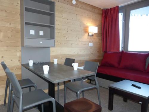 une chambre avec une table, des chaises et un canapé rouge dans l'établissement Studio cozy aux pieds des pistes, balcon, animaux admis - FR-1-181-2575, à Aime La Plagne