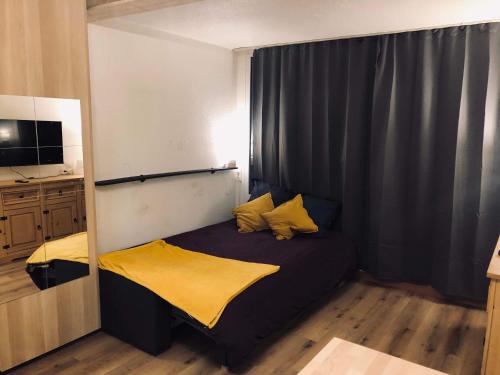 Dormitorio pequeño con cama con almohadas amarillas en Appartement Alpe-d'Huez 4 Personnes en L'Alpe-d'Huez