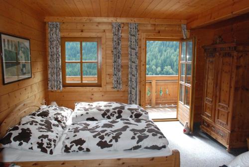 Wastlbauer - Luxus Chalet mit Wohlfühlfaktor في Vorderwald: غرفة نوم مع سرير مع أوراق مطبوعة للبقر