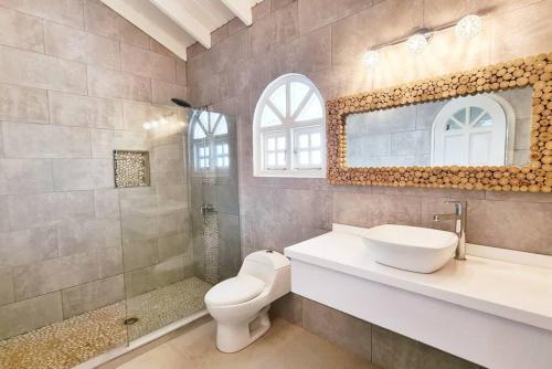 a bathroom with a toilet and a sink and a mirror at Beach Walk Residences in Palm-Eagle Beach