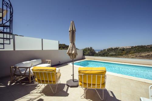 a patio with chairs and an umbrella and a swimming pool at 401 Villa Salemar in Salema