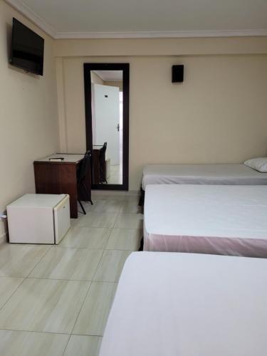 a bedroom with two beds and a desk and a mirror at Hotel Estação Express in Curitiba