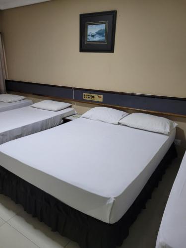 two beds in a room with white sheets at Hotel Estação Express in Curitiba