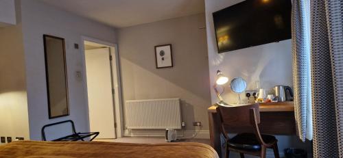 a bedroom with a bed and a desk and a television at The Cross-Keys Hotel in Knutsford