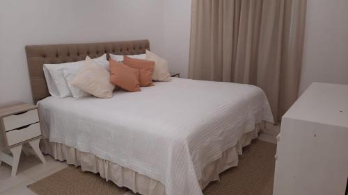 1 dormitorio con 1 cama con sábanas y almohadas blancas en La Herradura en Pinamar