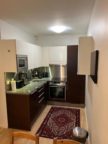 a small kitchen with white cabinets and a rug at Modern 45m^2 Ullanlinna apartment in Helsinki