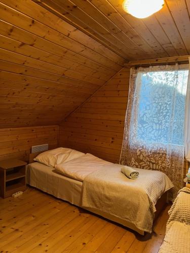a bed in a wooden room with a window at Chata pod Skrzycznem LuLu in Szczyrk