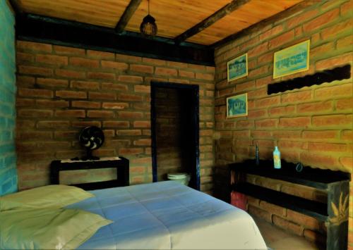 1 dormitorio con cama y pared de ladrillo en Hostel CASA DA PEDRA CHATA en Torres