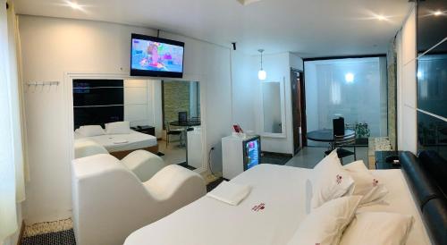 uma sala de estar com mobiliário branco e uma televisão na parede em Studio Motel (Adult Only) em Santos