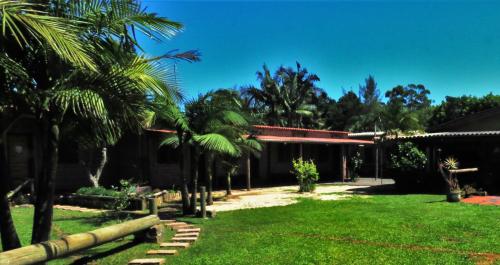 a yard with palm trees and a building at Hostel CASA DA PEDRA CHATA in Torres