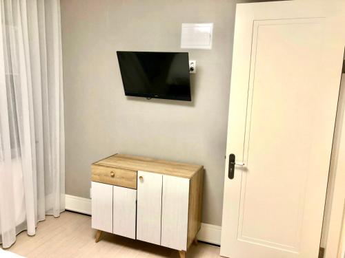 Zimmer mit einem TV an der Wand und einem Holzschrank. in der Unterkunft The Trust Highvill Ishim D in Astana