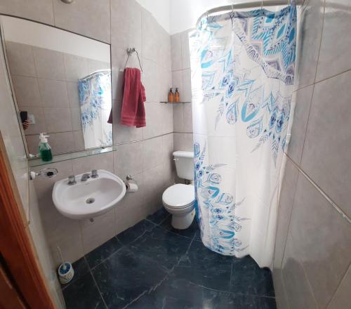 y baño con lavabo, aseo y cortina de ducha. en De paso primo camas simples cochera con rejas sin techo en Villa María