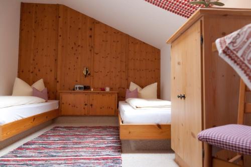 two beds in a room with wooden walls at Landhaus Reiser in Grainau