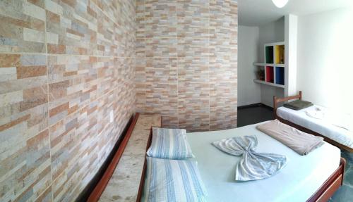 a bedroom with a bed and a brick wall at Da Orla Pampulha Hostel in Belo Horizonte