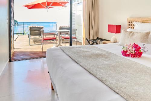 a bedroom with a bed and a balcony with a table at LES GALETS ROUGES LODGES & SPA in Bouillante