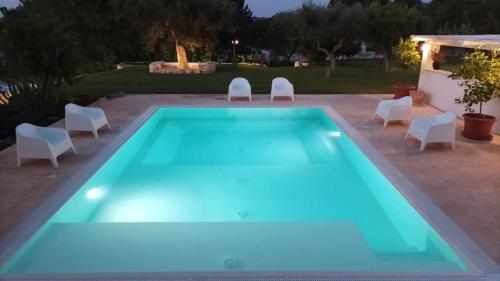 une grande piscine entourée de chaises blanches. dans l'établissement Casale Romanazzi Pool & Nature, à Monopoli