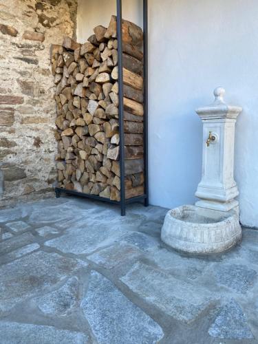 a pile of fire wood next to a wall with a fire hydrant at Experience in Valle Varaita - Rustico con SPA Privata - Piscina - Sauna - Hammam - Free Wi-Fi in Brossasco
