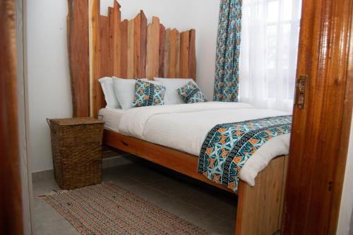 a bed with a wooden headboard in a room at Nook-HeArt Stays in Kakamega