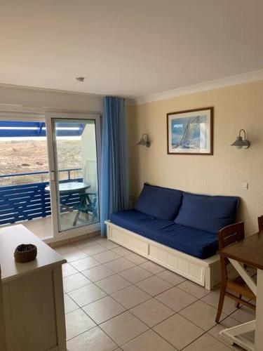 - un canapé bleu dans une chambre avec balcon dans l'établissement Agréable T2 Lacanau Ocean bord de mer. Expo sud., à Lacanau-Océan