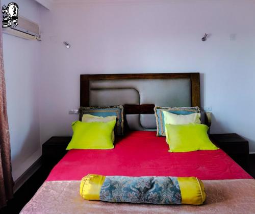 un letto con 2 cuscini gialli e una coperta rossa di Hotel Le Relais Normand a Antananarivo