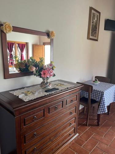 a dresser with a vase of flowers on top of it at Agriturismo IL VIAIO in Fiesole