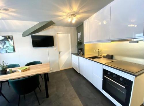 a kitchen with white cabinets and a wooden table at Topp Leilighet ski inn ski out Gautefall in Drangedal