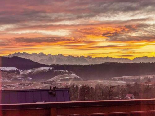 a sunset over a valley with mountains in the background at Loft&Hill in Grywałd