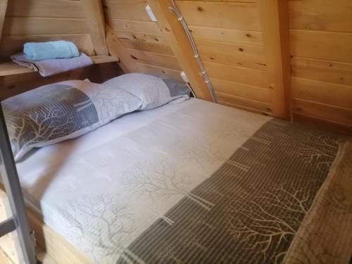 an empty bed in a room with wooden walls at Tarska Bajka in Bajina Bašta