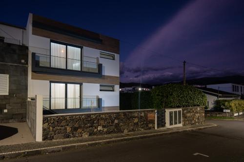 a building with a stone wall next to a street at Lugar d ribeira in Lagoa