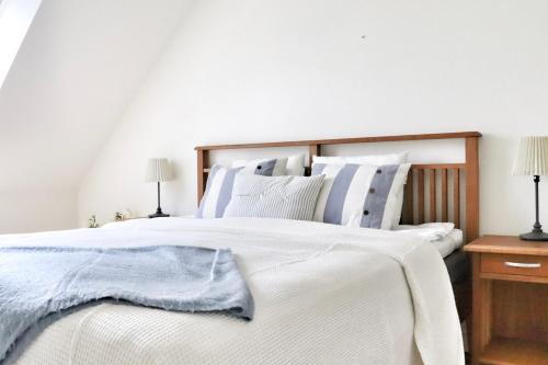 a bedroom with a white bed with a blue blanket on it at Mysigt hus med kamin och pool in Torekov