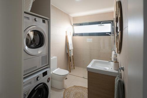 een kleine badkamer met een wasmachine en droger bij Lugar d ribeira in Lagoa