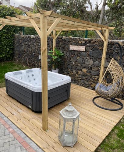 a hot tub under a pergola on a wooden deck at Lugar d ribeira in Lagoa