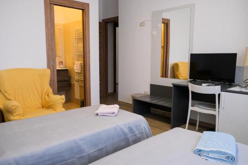 a room with two beds and a television and a chair at Dimora Cice in SantʼAgata deʼ Goti