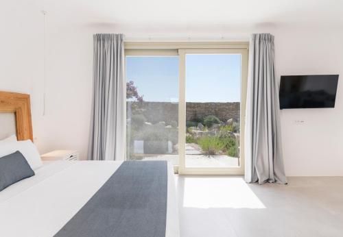 um quarto com uma cama e uma grande janela em My Castle House - MG Villas Mykonos em Fanari