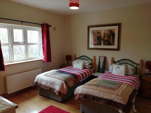 a bedroom with two beds and two windows at Rosswood House in Donegal