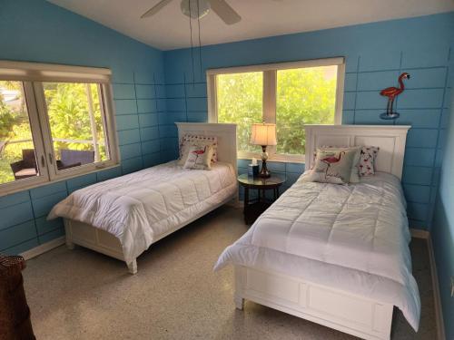 two beds in a room with blue walls and windows at The Butterfly Cottage in Marathon