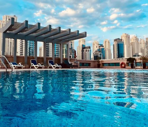 Fabolous Vacation Home in Dubai Marina في دبي: مسبح على أفق المدينة في الخلفية