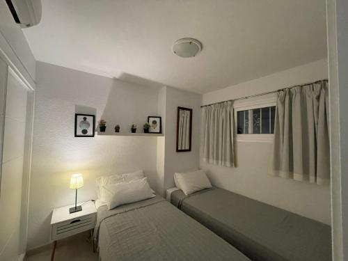 sypialnia z dwoma łóżkami, stołem i oknem w obiekcie Cielomar Benalmadena costa w mieście Benalmádena