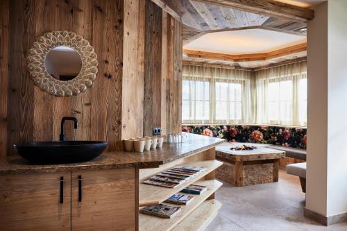 baño con paredes de madera, lavabo y banco en Hotel Garni Ransburgerhof en Flachau