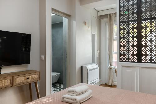 Well Apartments by Skyloft Corfu في Anemómylos: غرفة نوم بسرير وتلفزيون وحمام